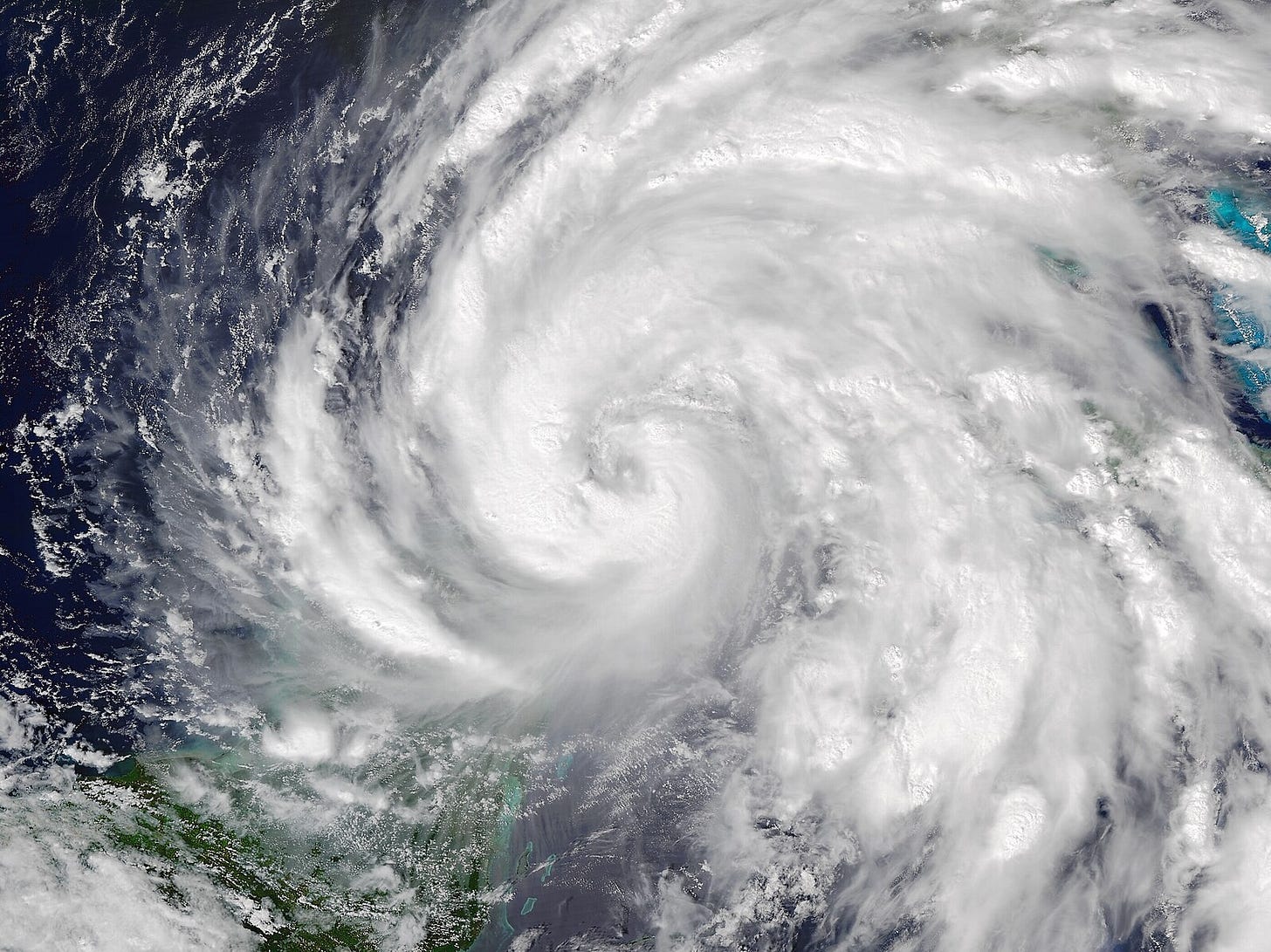 An overhead shot of the spiral cloud formation of a large hurricane over the ocean.