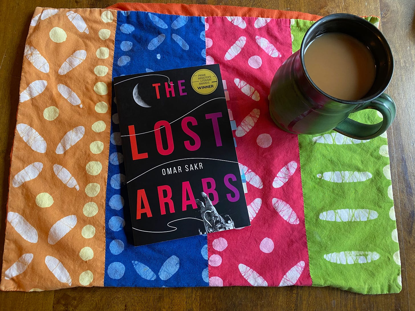 The Lost Arabs on a colorful placemat next to a mug of tea.