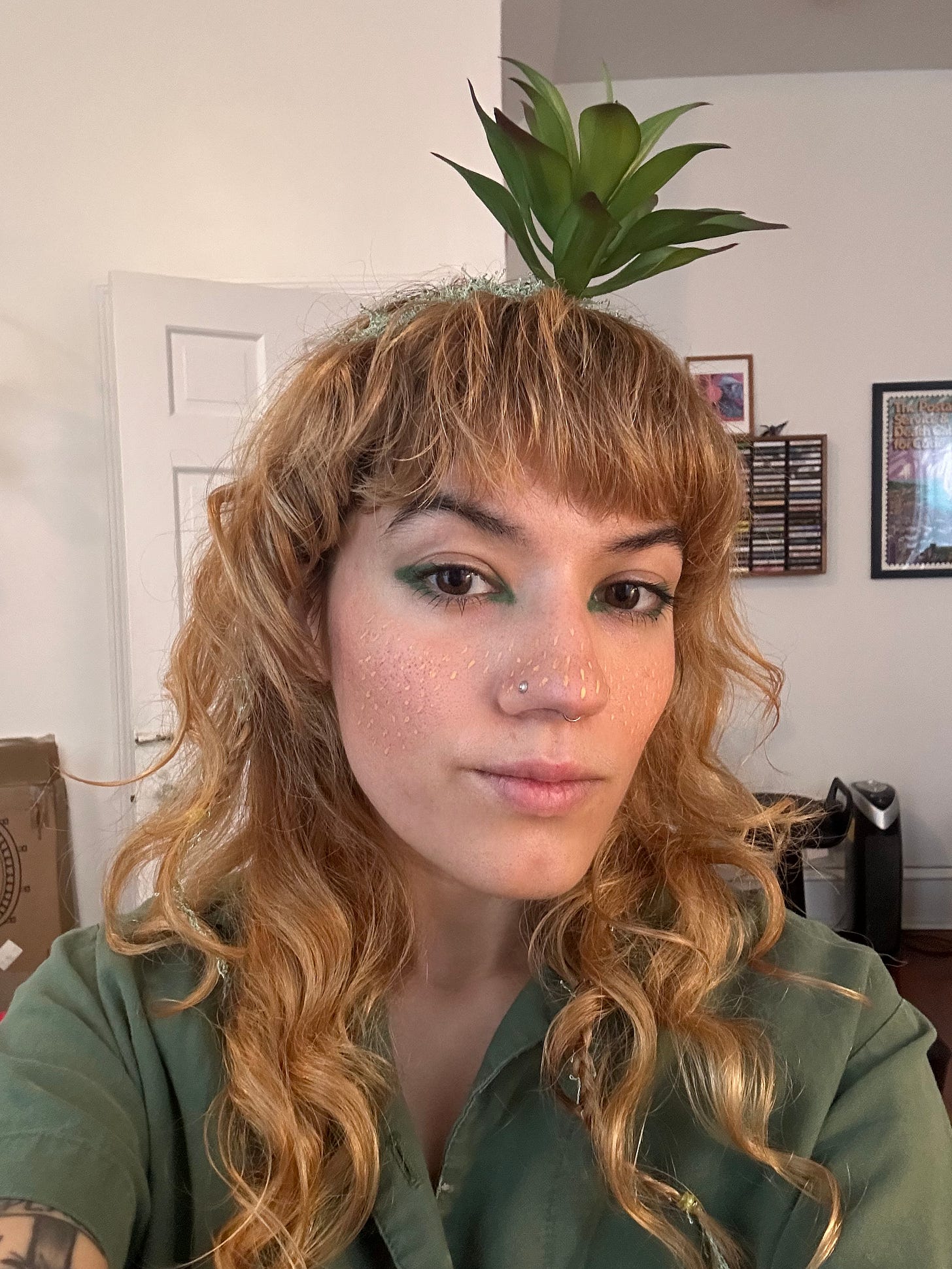 CB wears a headpiece like the top of a strawberry, plus strawberry cheeks and striking green eyeliner.