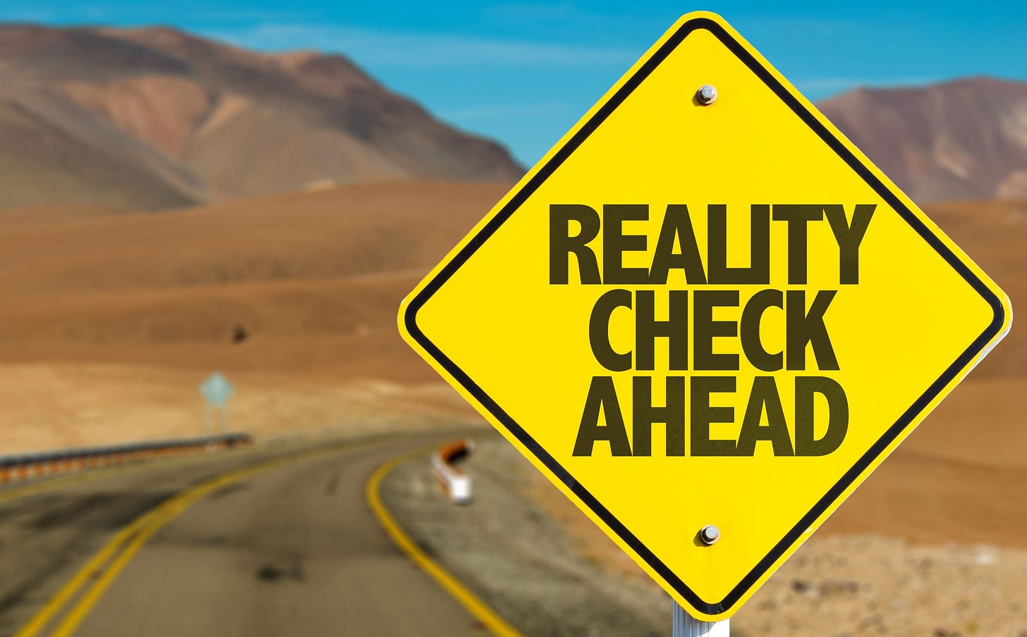 Open road with yellow road sign reading, "REALITY CHECK AHEAD."