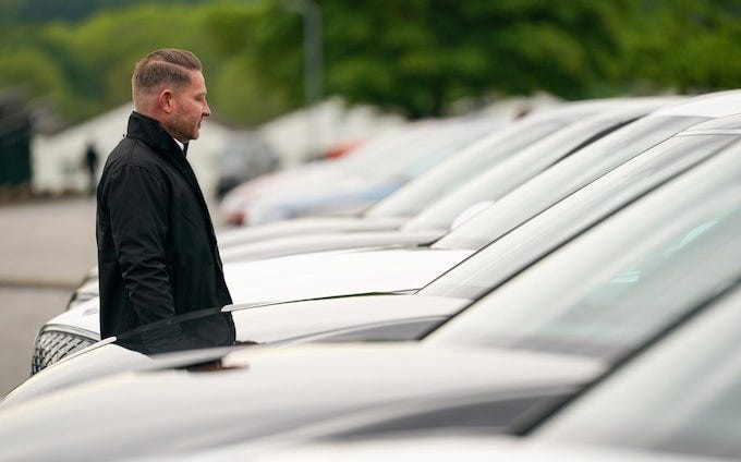 A man stands between a row of electric cars