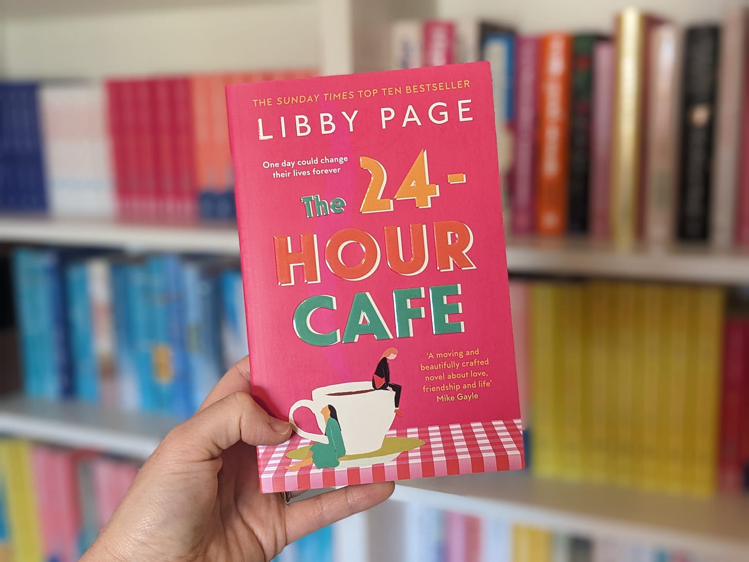 The cover for Libby Page's The 24-Hour Café is a deep pink and shows two women turned away from each other, sat on a tea cup.