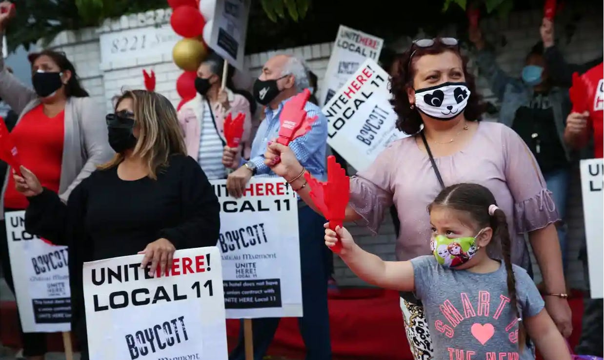 Former employees of the Chateau Marmont protest in masks, including a small child. 