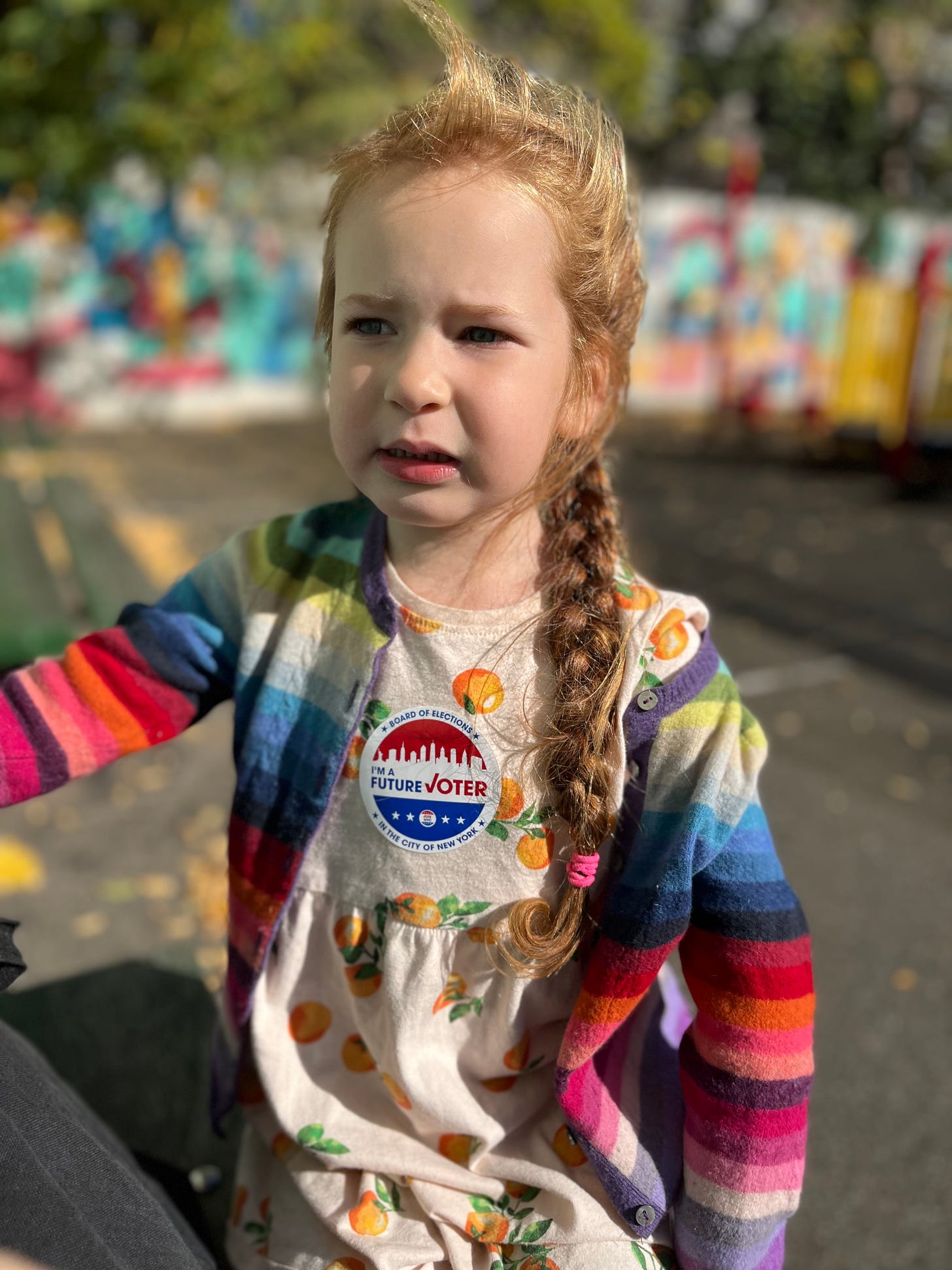 Mirah, a then 5-year-old girl in a rainbow striped cardigan, with a sticker on her chest that says “I’m a future voter”