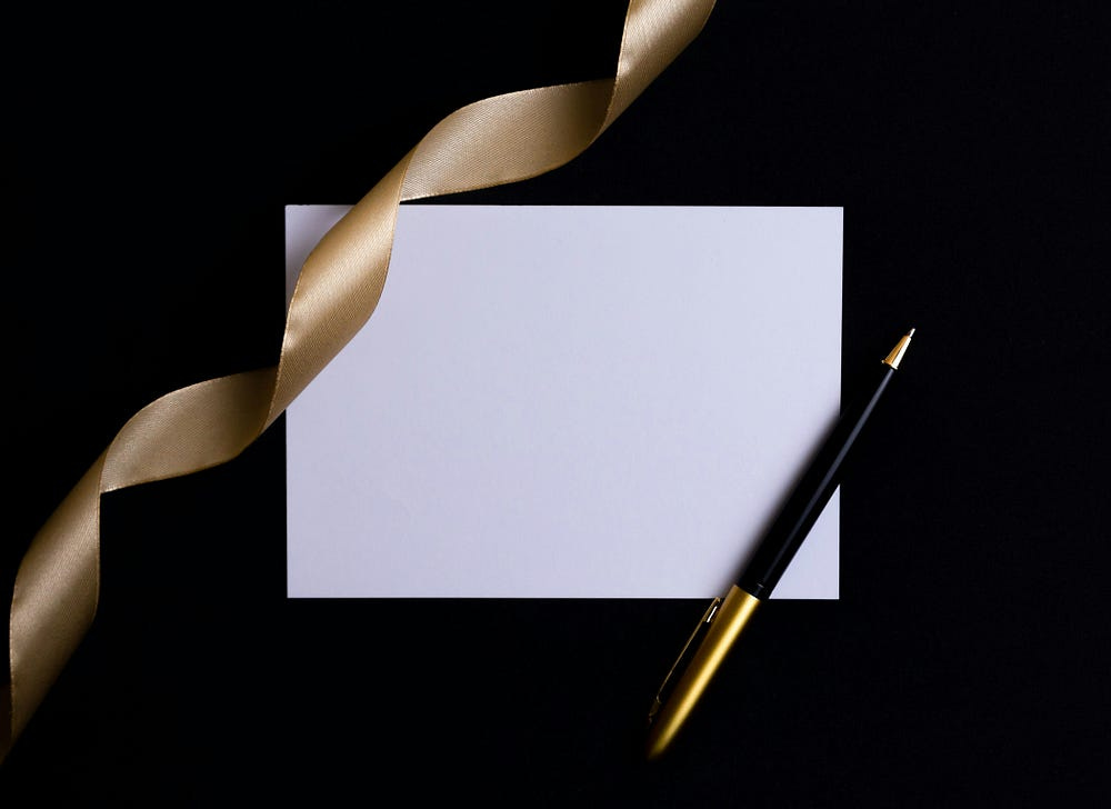 Blank Invitation, with a gold ribbon and a black, gold pen, on a black background.