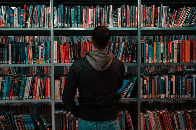 Man looking at books on shelves.