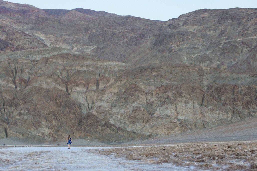 Chelsea walks across Badwater in Death Valley NP. There's a tiny white sign on the cliff above her that reads, "Sea Level."