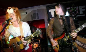 A photo of Tiny Dancers performing live with lead-singer, David Kay, wearing a hat featuring a cuddly lion's head A photo of Tiny Dancers performing live with lead-singer, David Kay, wearing a hat featuring a cuddly lion's head