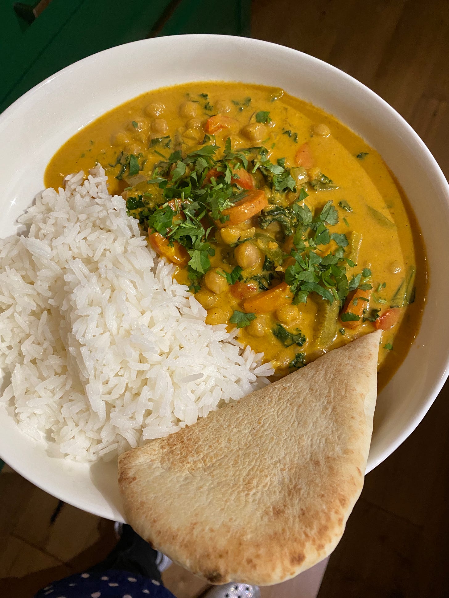 bowl of coconut curry with naan and rice