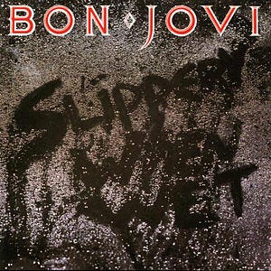 The album title written in the water droplets on a black surface; above is the Bon Jovi logo in red.