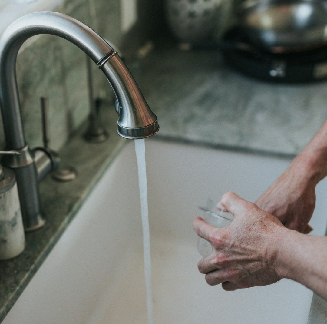 person washing hand on faucet person washing hand on faucet