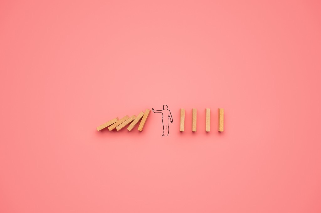 Illustration of a figure stopping a series of dominos from falling.