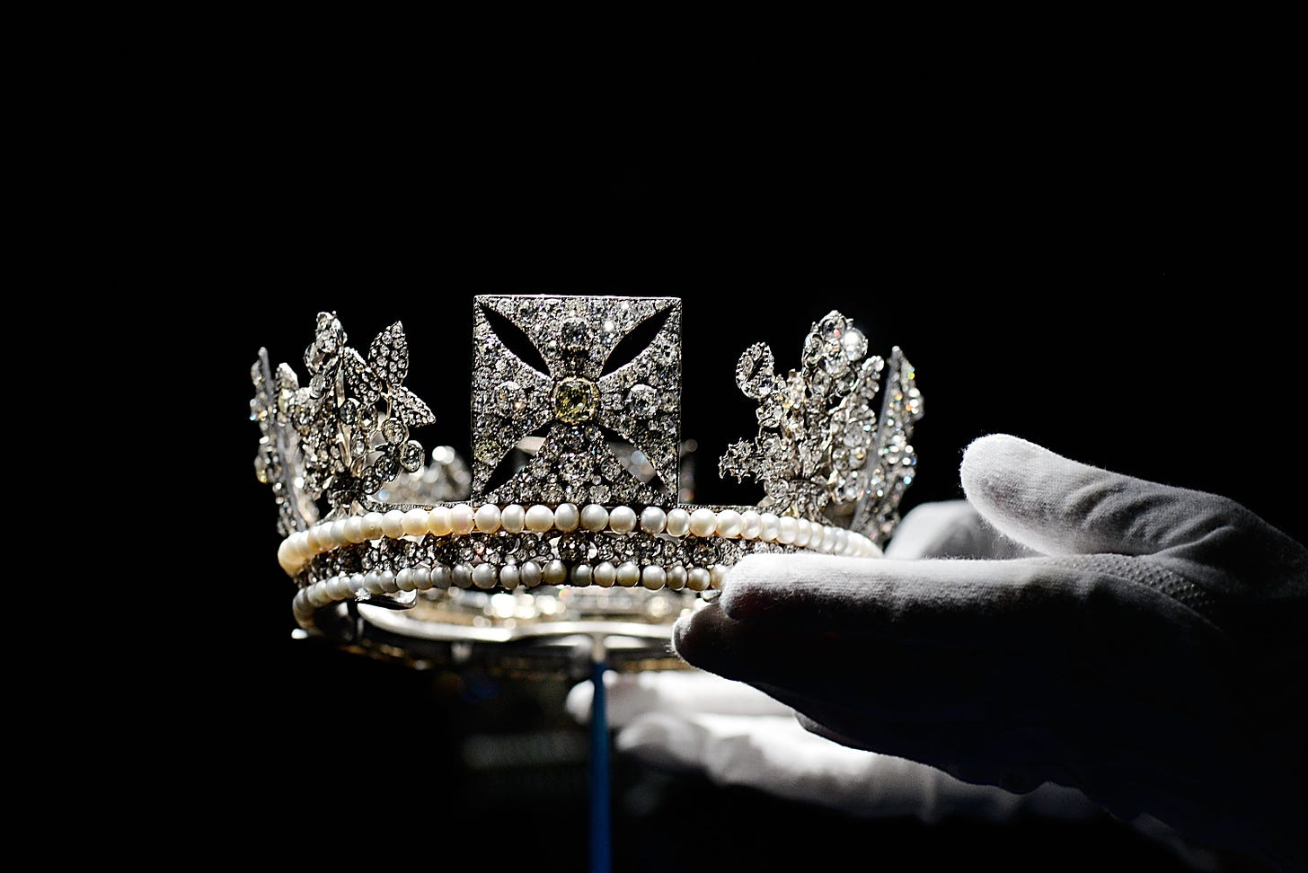Close-up of the diamond diadem held by hands wearing white gloves