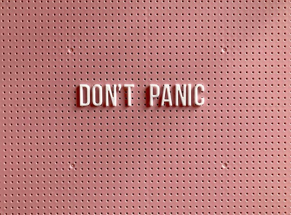 “Don’t Panic”, the words are on a pink background, in white letters.