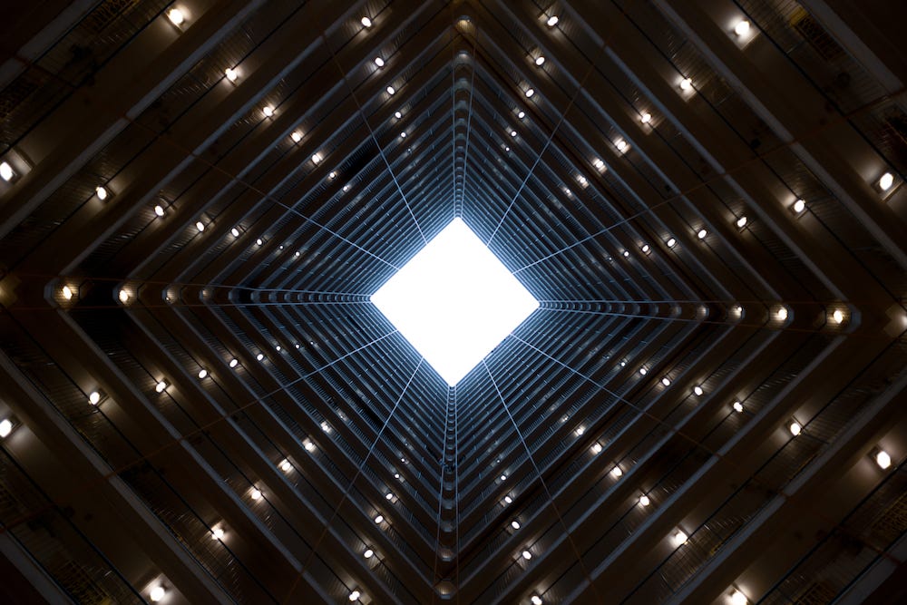 Skylight view of a dark futuristic structure with a uniform series of tiny lightbulbs