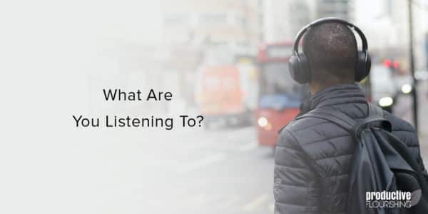 Man wearing big headphones in a city. Text overlay: What Are You Listening To?