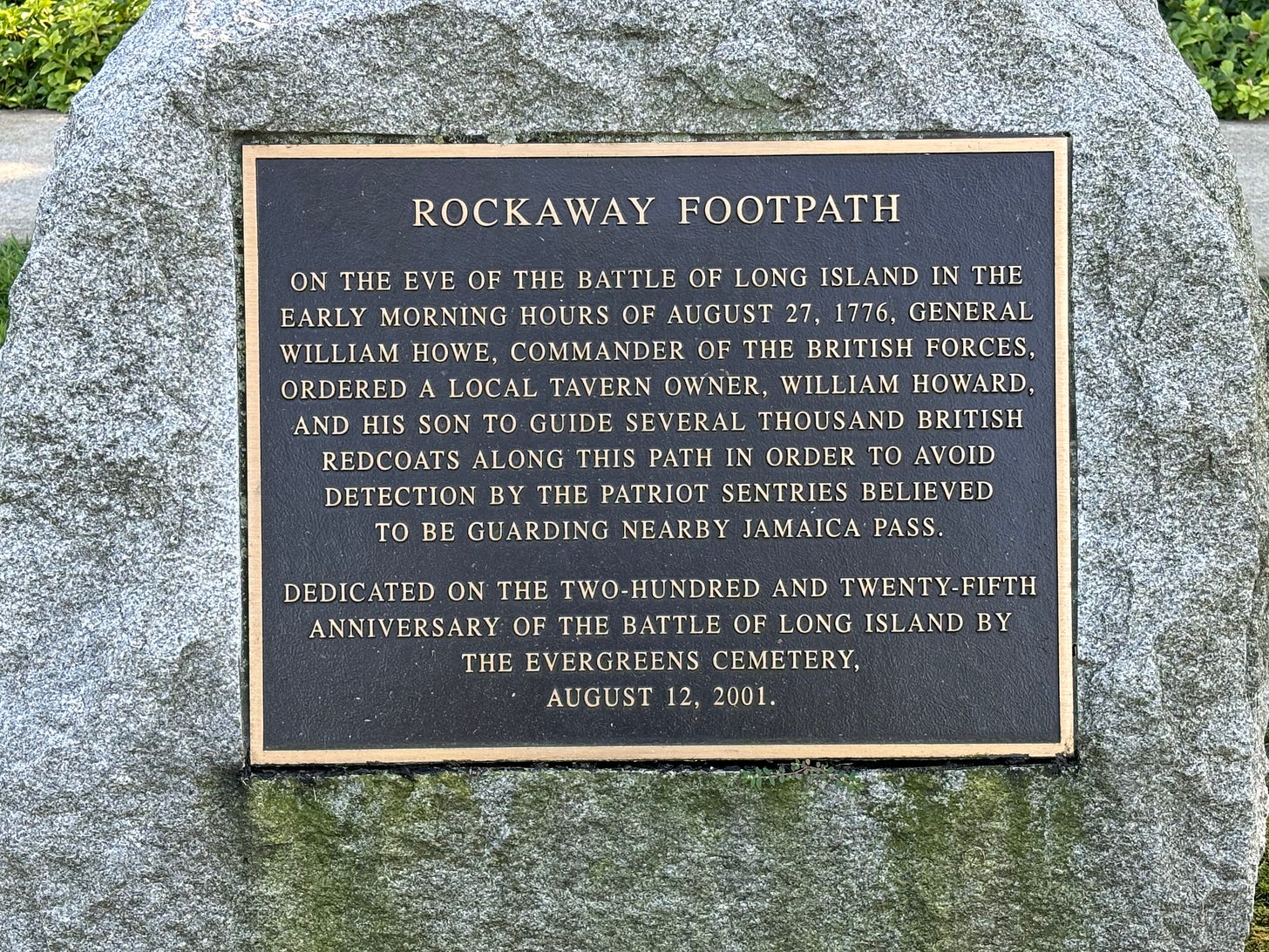 A close-up of the Rockaway Footpath plaque. It reads: On the eve of the Battle of Long Island in the early morning hours of August 27, 1776, General William Howe, commander of the British forces, ordered a local tavern owner, William Howard, and his son to guide several thousand British redcoats along this path in order to avoid detection by the patriot sentries believed to be guarding nearby Jamica pass.  Dedicated on the two-hundred and twenty-fifth anniversary of the Battle of Long Island by the Evergreens Cemetery, August 12, 2001.