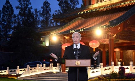 Vladimir Putin speaking in Beijing from a podium in front of a brightly-illuminated, traditional-looking Chinese building