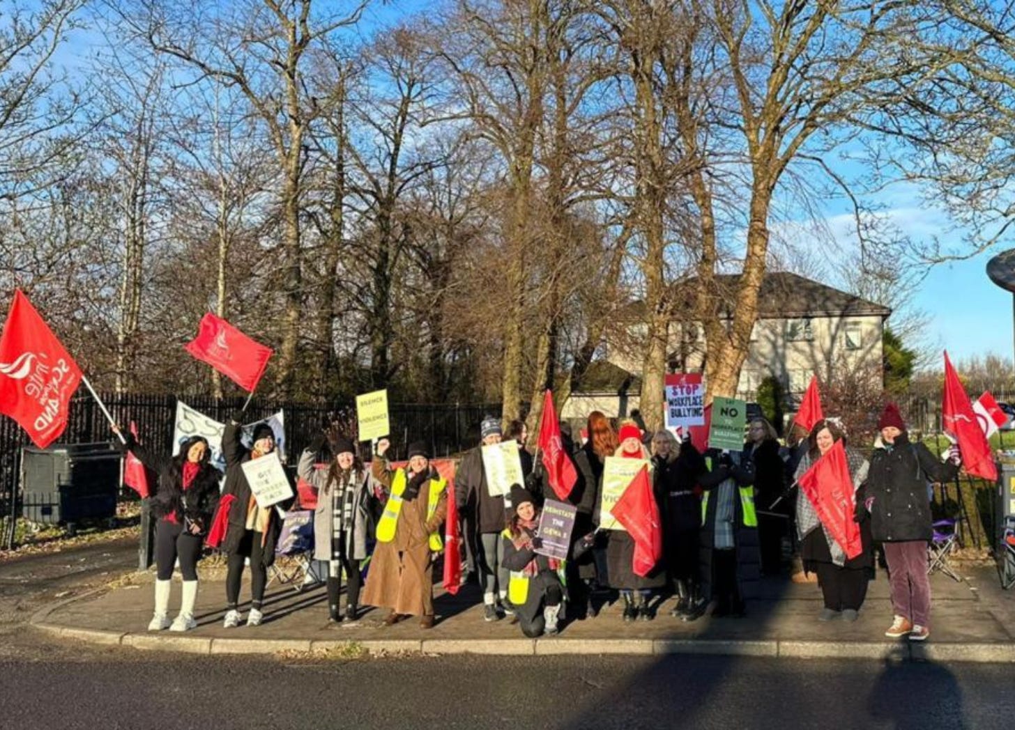 Women strike with flags outside women's aid centre.