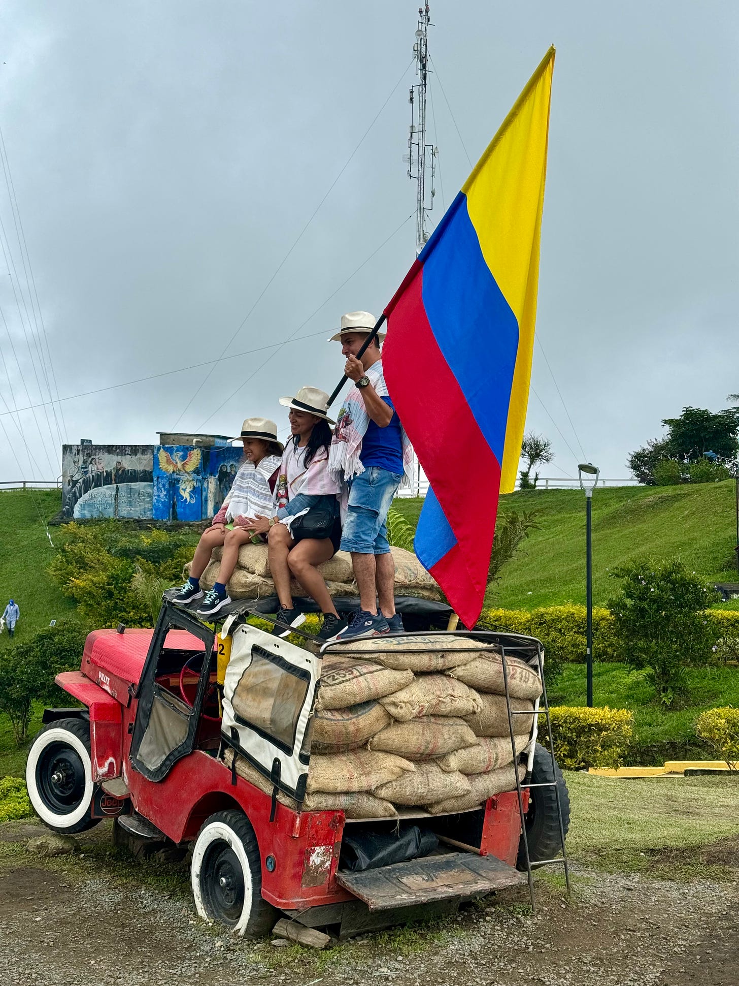 Una familia colombiana sobre un willy turístico cargado de café sostienen la bandera colombiana para hacerse una foto. Foto propia. 