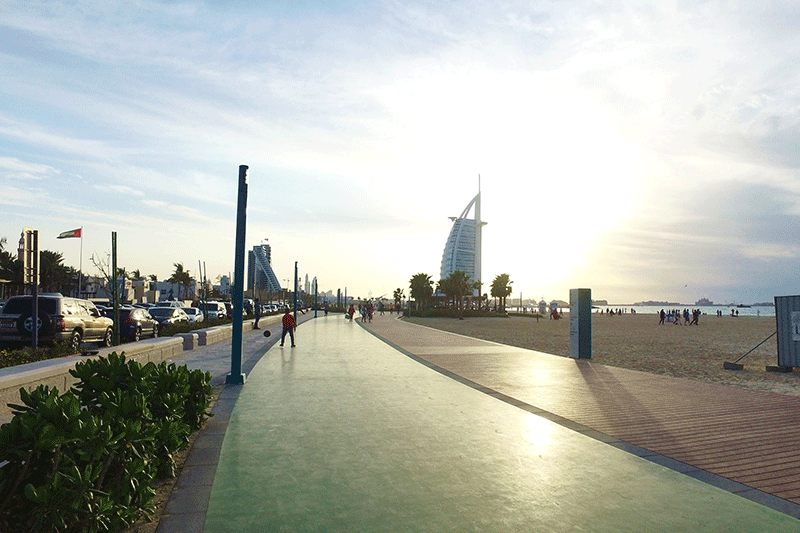 photo of a jogging path that is on the side of a Dubai beach. A view of Burj Al Arab can be seen from a distance photo of a jogging path that is on the side of a Dubai beach. A view of Burj Al Arab can be seen from a distance