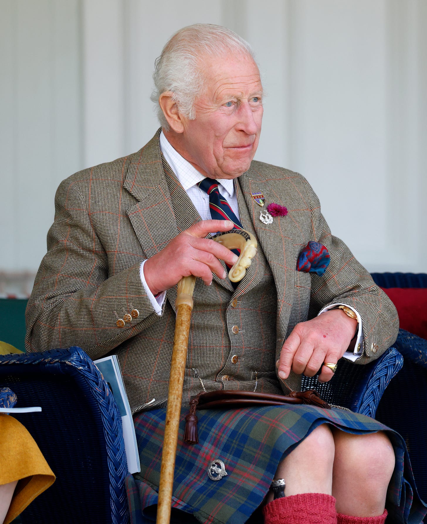 King Charles sat down holding a walking stick