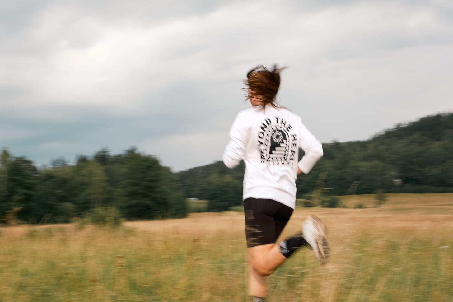 Female runner with a white shirt running over a field