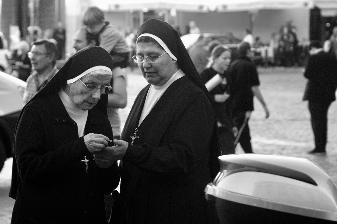 A group of nuns looking at a cellphone

Description automatically generated