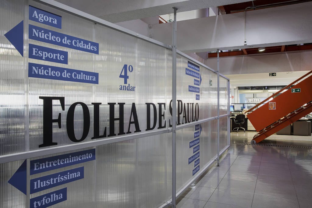 Foto do 4º andar de redação da Folha de SP, onde se vê divisória apontando a direção de Editorias e escada ao fundo.