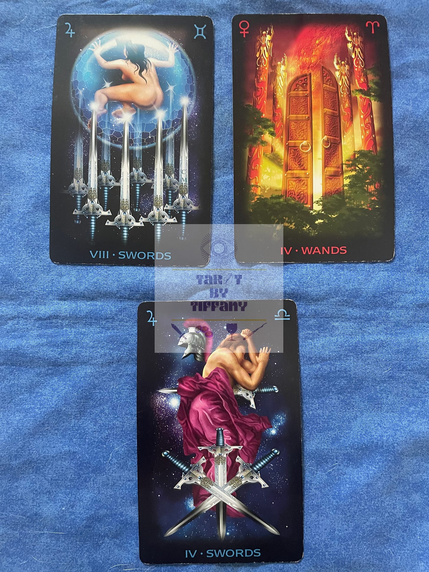 3-card reading with the Tarot of Dreams by Ciro Marchetti. The cards are laid out on a cobalt blue cloth background. Top two cards (L-R): 8 of Swords and 4 of Wands. Bottom card: 4 of Swords.