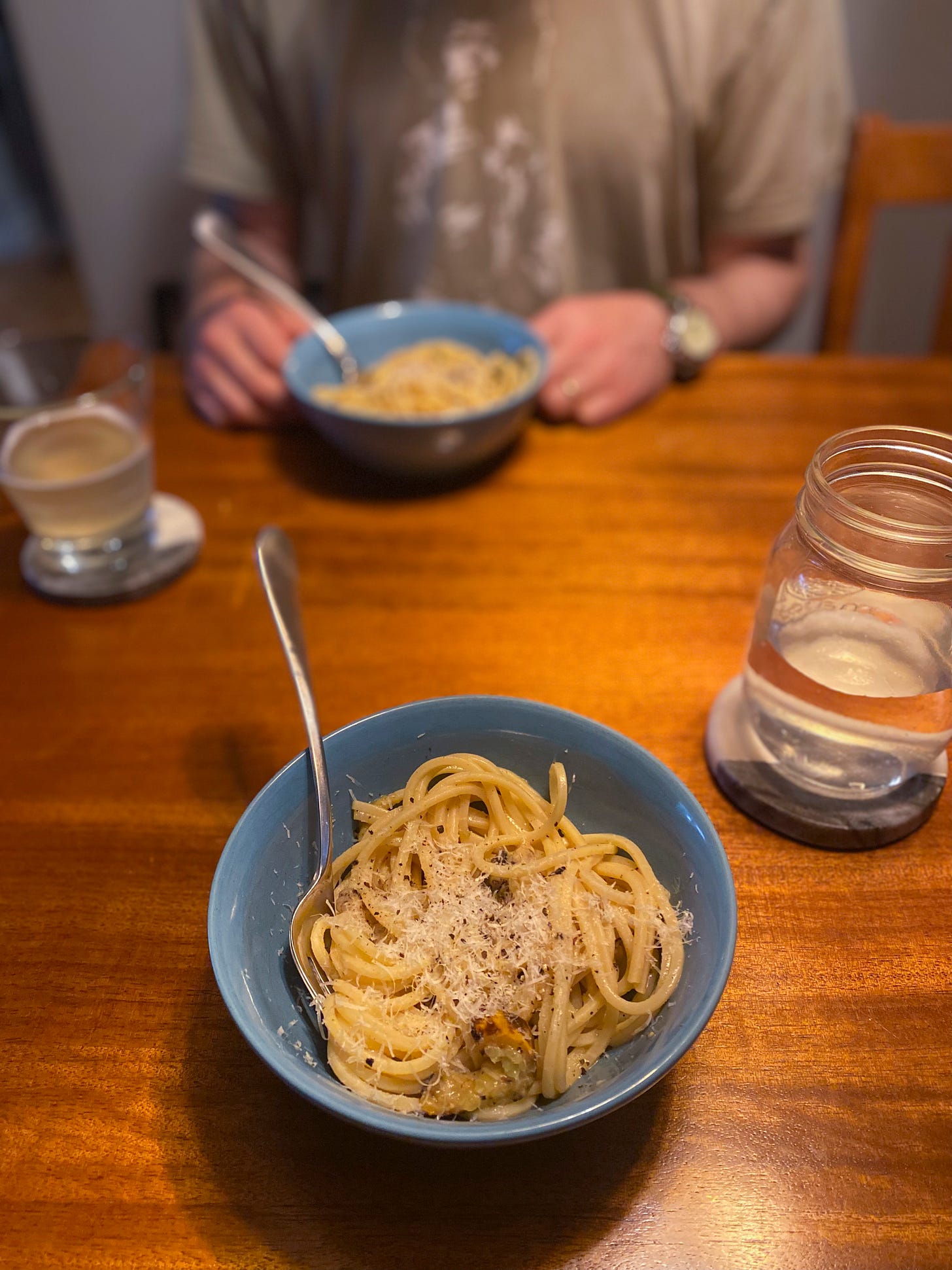 Two blue bowls of spaghetti quadrato with yellow zucchini and pecorino.