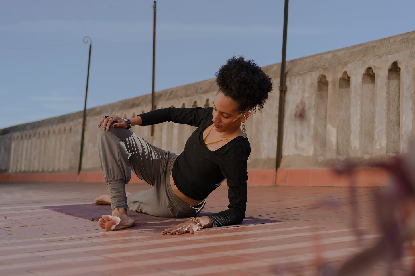black woman doing morning yoga outdoors in a sunny rooftop patio