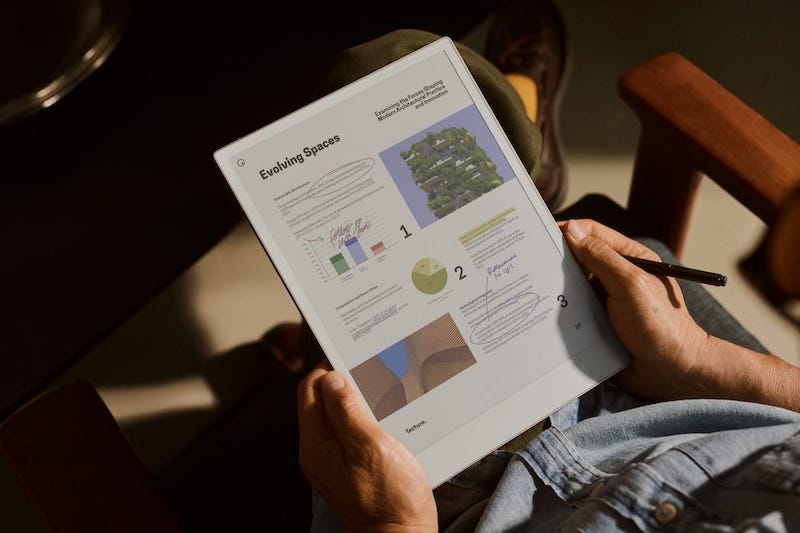 An image of a man sitting down reading the reMarkable Paper Pro in colour