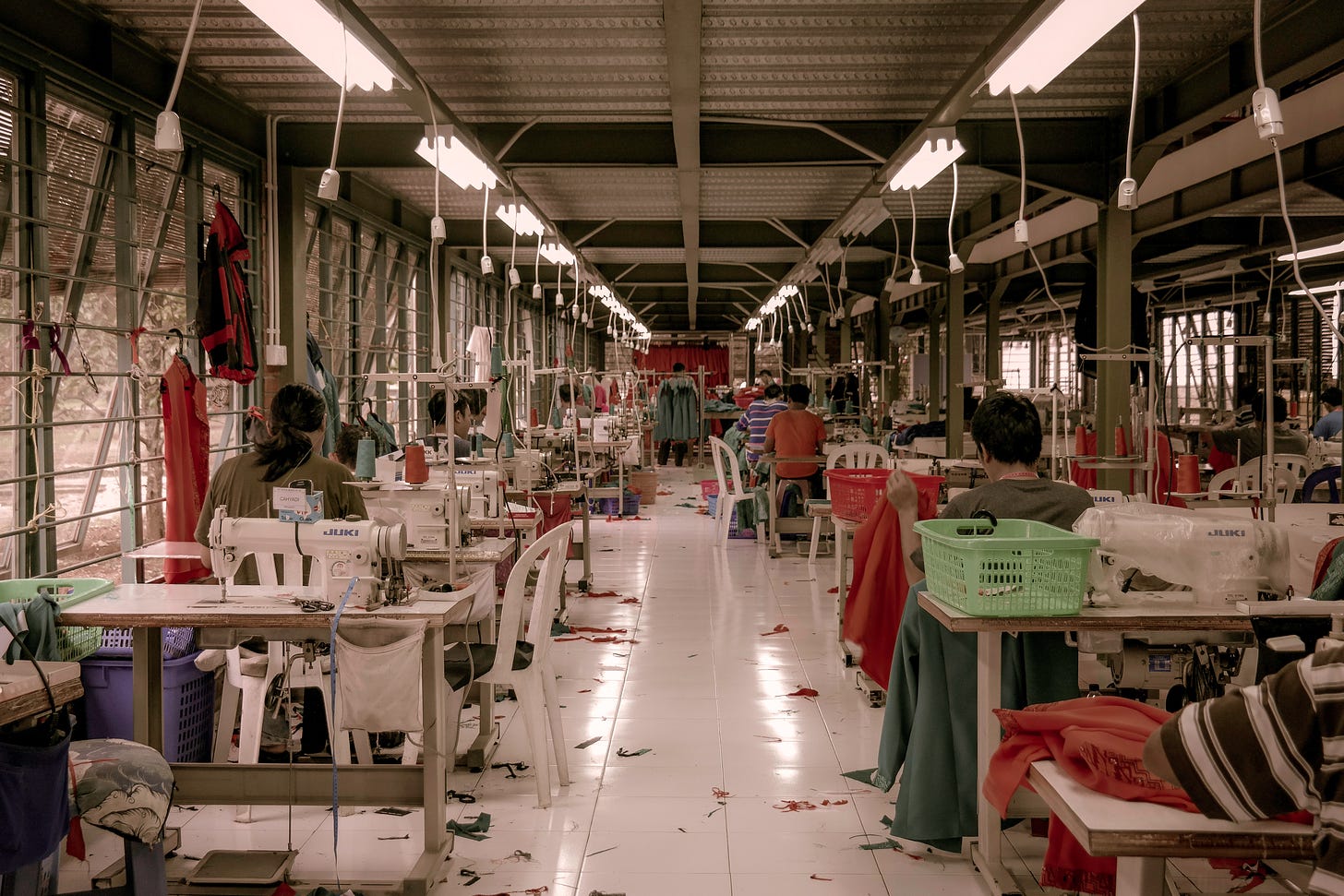 Image taken from the back of a clothing factory with workers sewing garments.