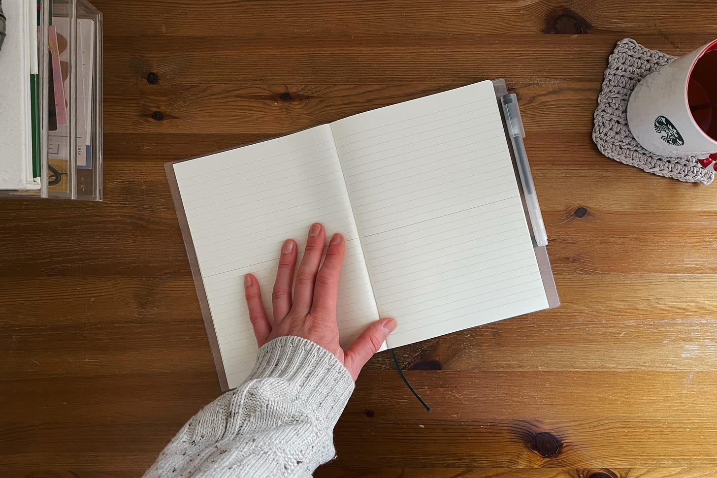 A flatlay of the open notebook resting on a blank page, with a hand gently placed on it.