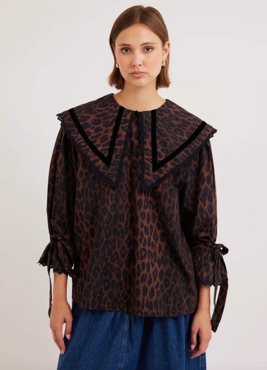 The Candice Blouse is our all over leopard print top featuring tie up detail sleeves, an oversized "V" collar and black broderie trims. 