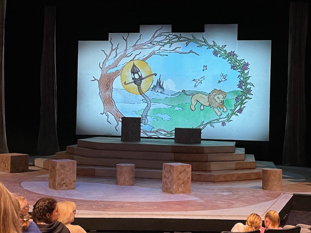 An empty stage with a backdrop of a lamppost and a lion, to illustrate The Lion, the Witch, and the Wardrobe
