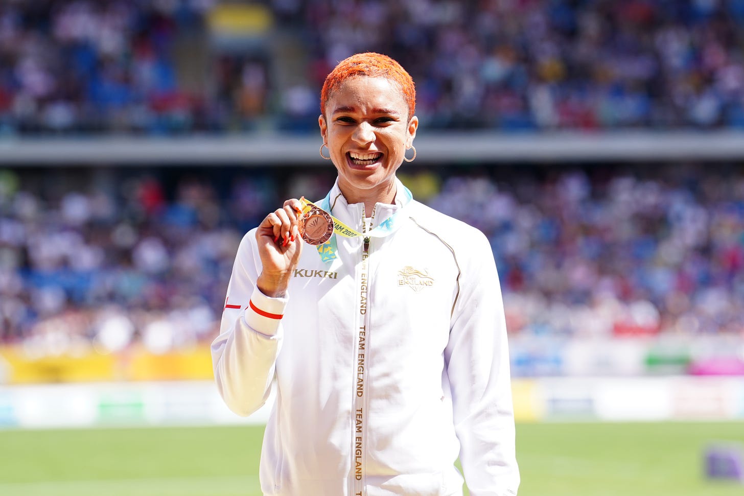 Jodie Williams smiling while clutching a bronze medal 