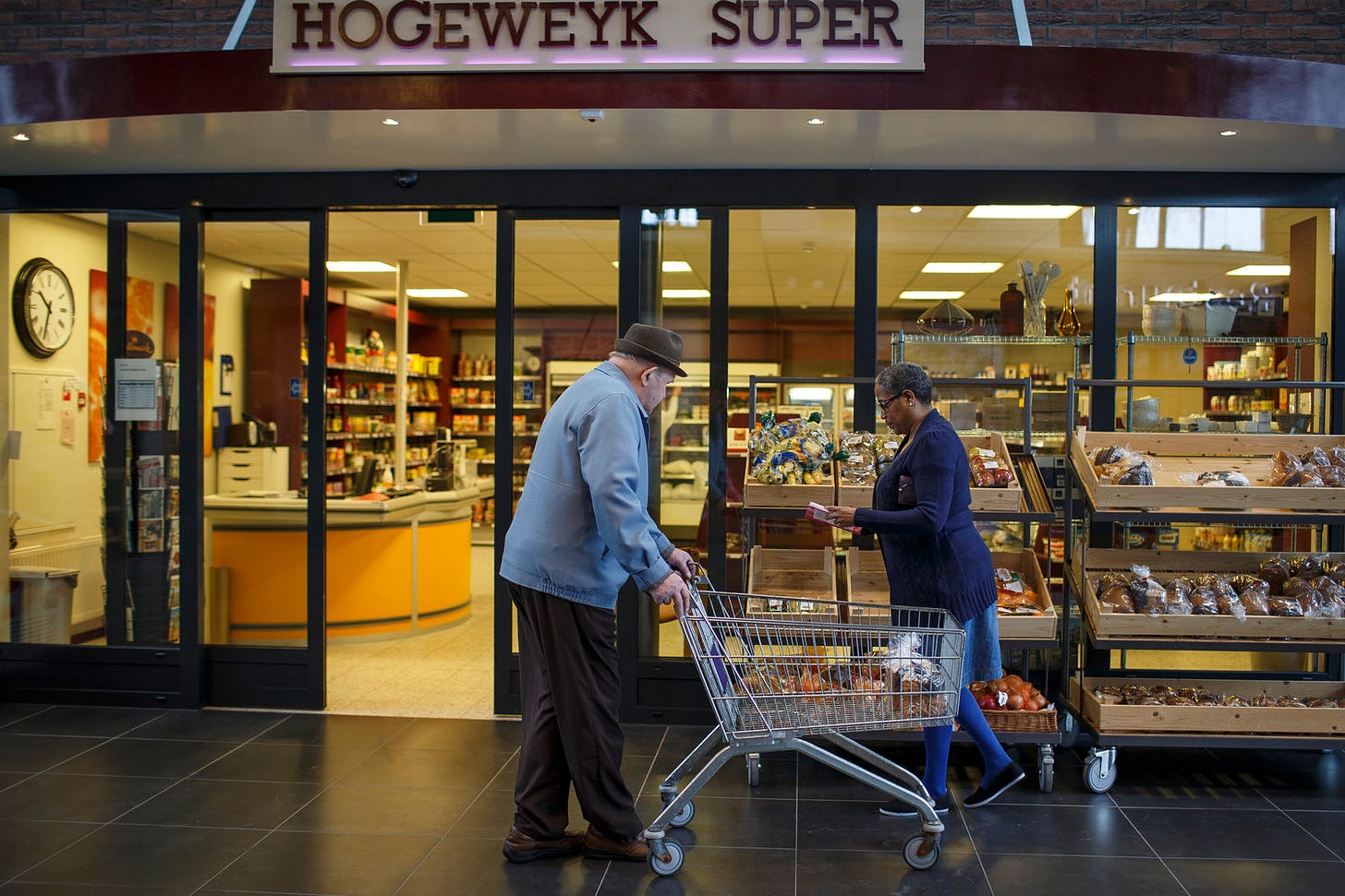 The exterior of the "Hogeweyk Super," the on-campus and operating grocery store, with shelves and register and carts in use.