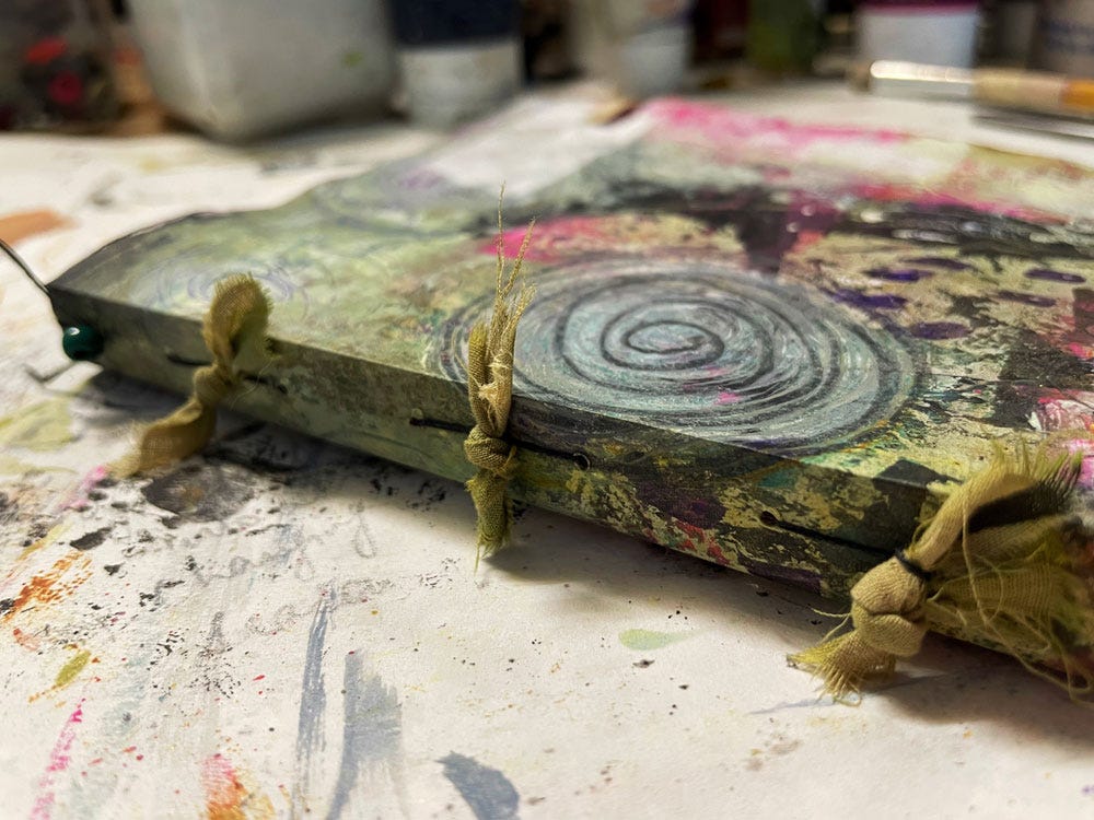 Image of a handbound book with a bead and fabric ties along the spine