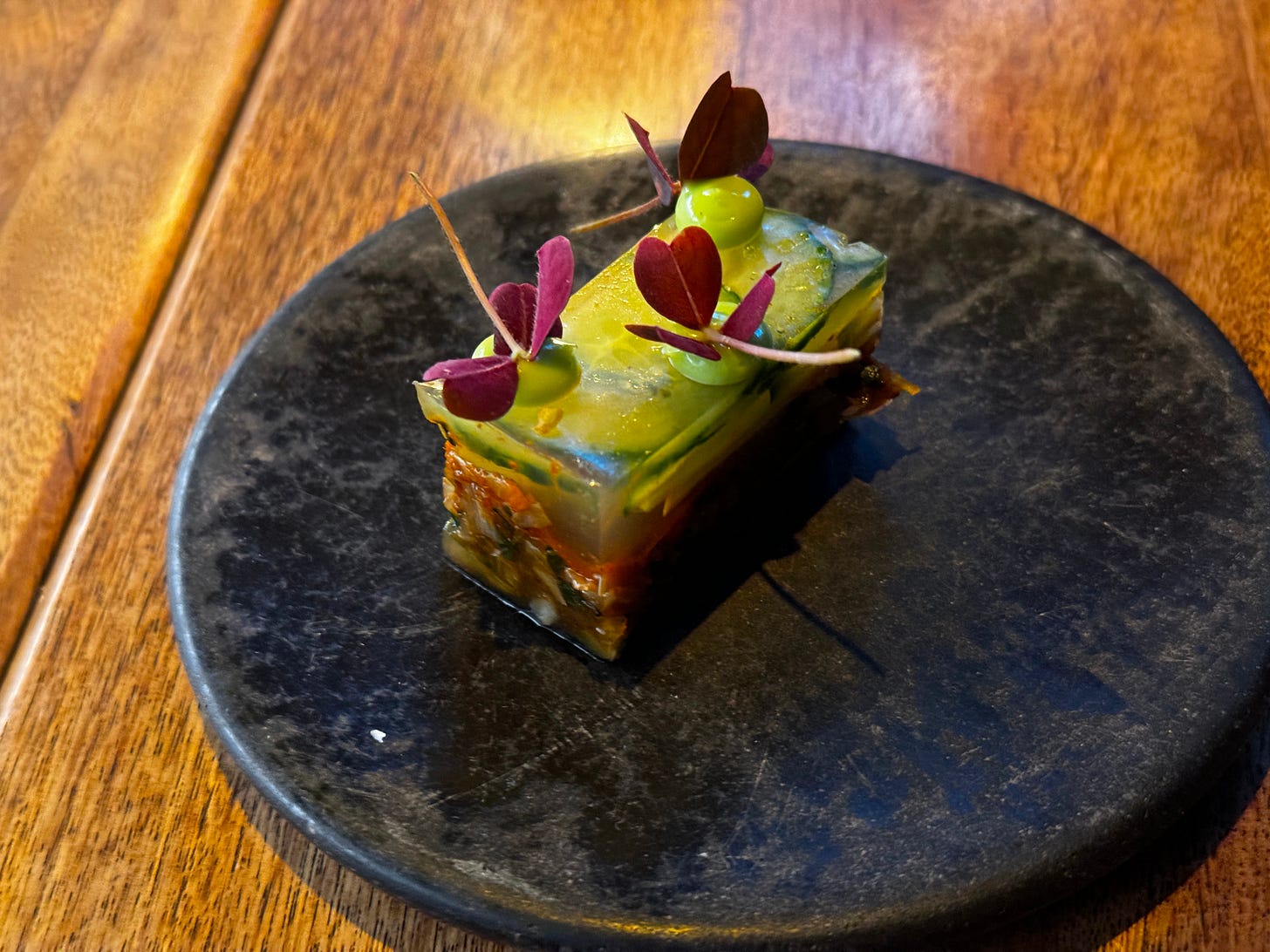 a vegetable pressed dish topped with purple flowers and served at Sud 777