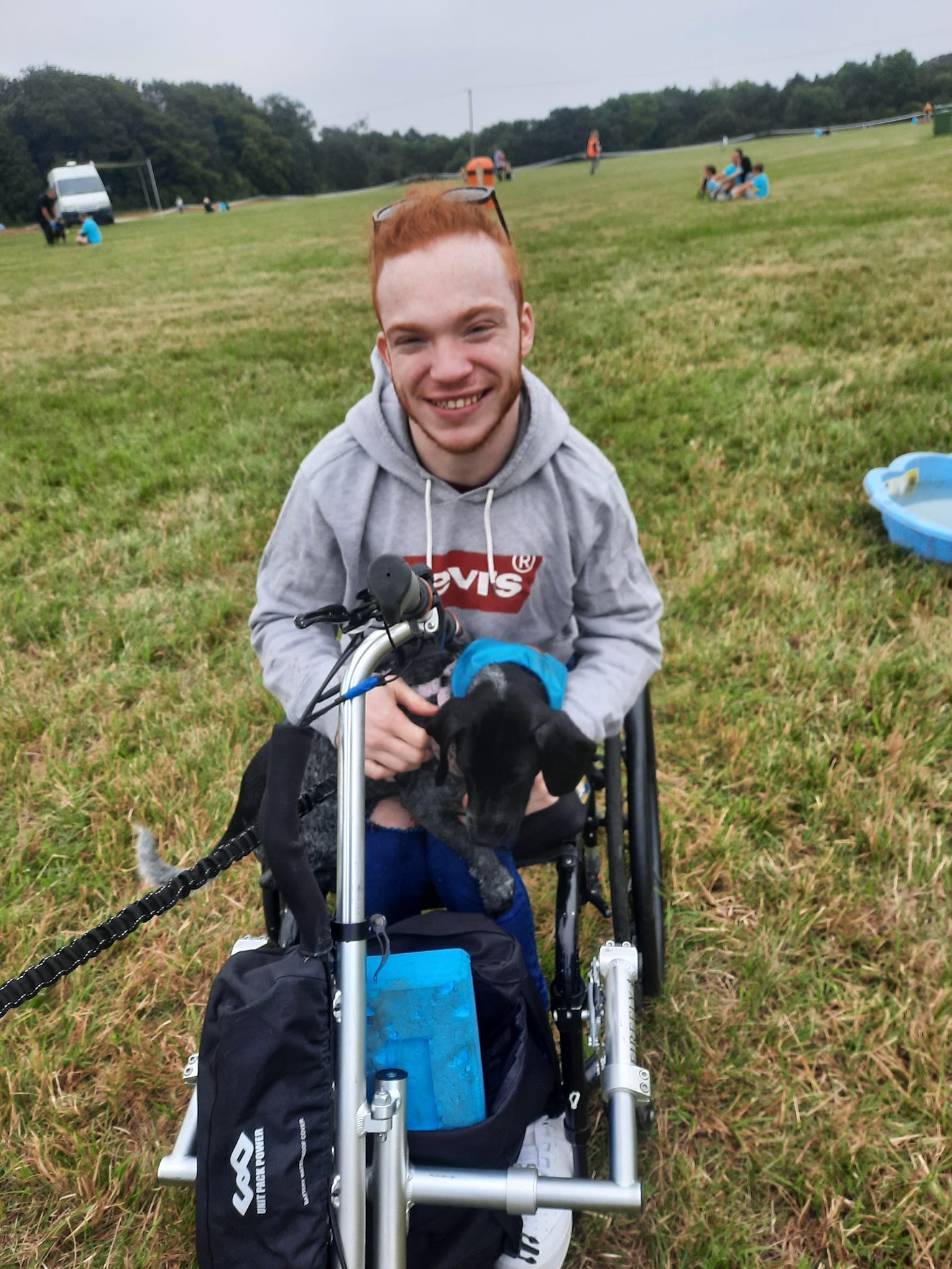 Charlie is a white man with ginger hair, sitting in a wheelchair with a dog on his lap