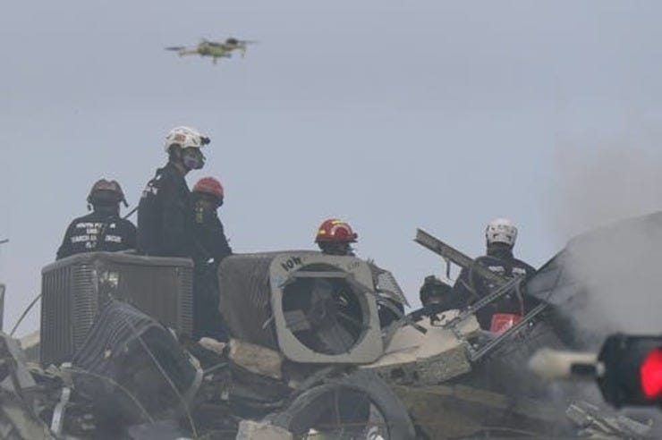 A drone flies above search and rescue personnel at the site of the Champlain Towers South Condo building collapse in Surfside, Florida. AP Photo/Wilfredo Lee