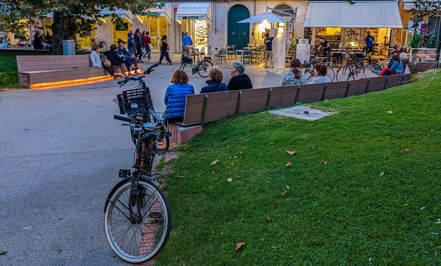 People of ages gathered in a park on an Italian evening. 