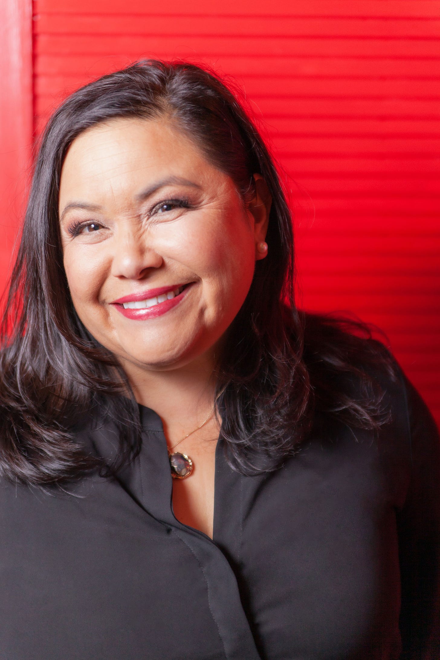 Theresa Gonzales in a black blouse against a red background