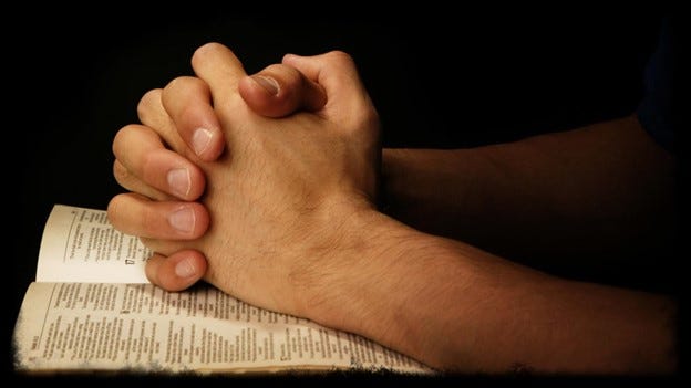 hands on Bible in prayer