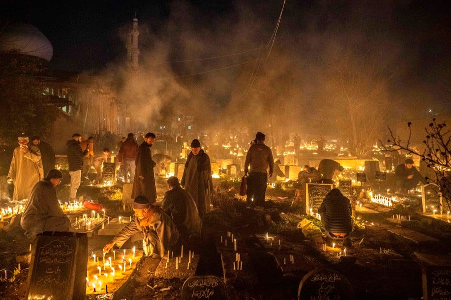 Many people visit a graveyard at night, lighting candles and praying.
