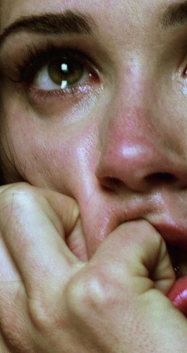 close up view on a young white woman who is crying, red nosed