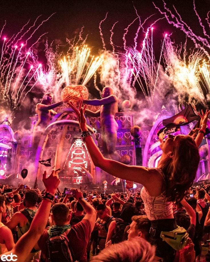 This may contain: a woman is holding up her cell phone in front of fireworks at an outdoor concert