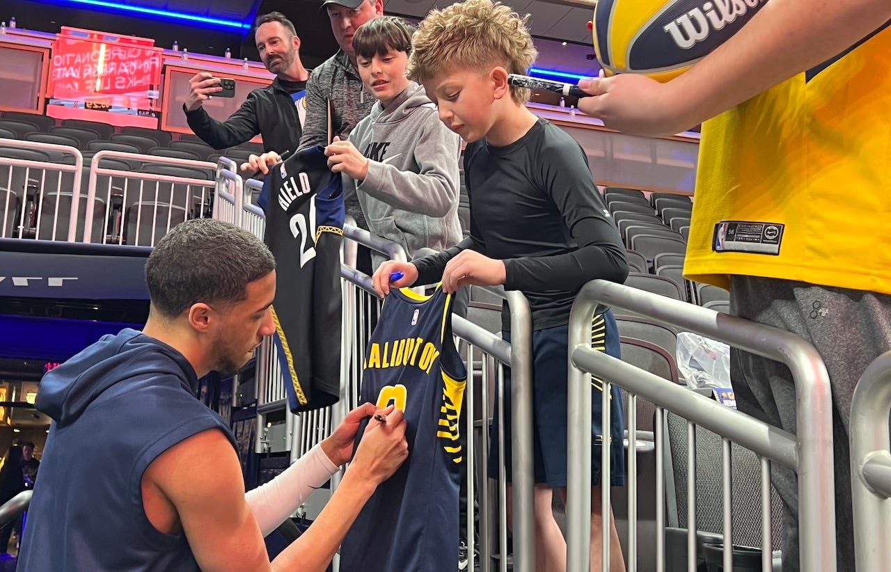 Tyrese Haliburton signs autograph for fan pregame.